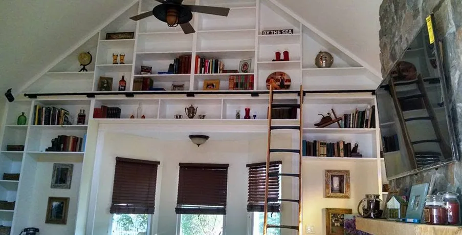 Floor-to-ceiling library built-ins with rolling ladder by North South Construction