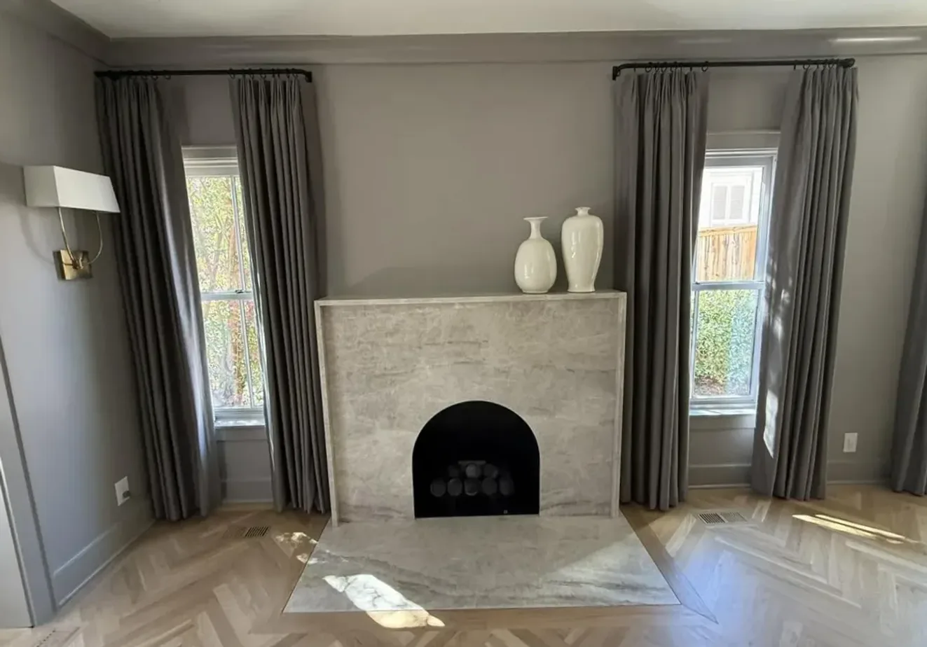 Marble fireplace surround and herringbone hardwood floor by North South Construction