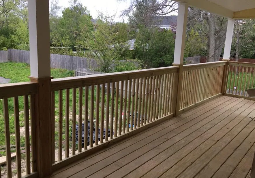 Covered porch and deck with wood railings by North South Construction