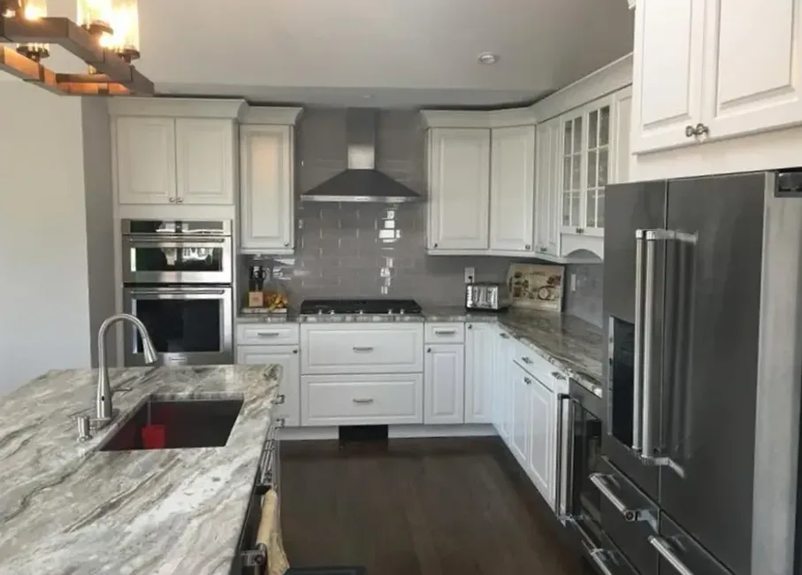 Kitchen remodel with white cabinets, gray subway tile, and granite island by North South Construction