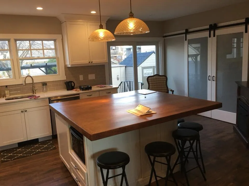 Kitchen remodel with butcher-block island and barn doors by North South Construction